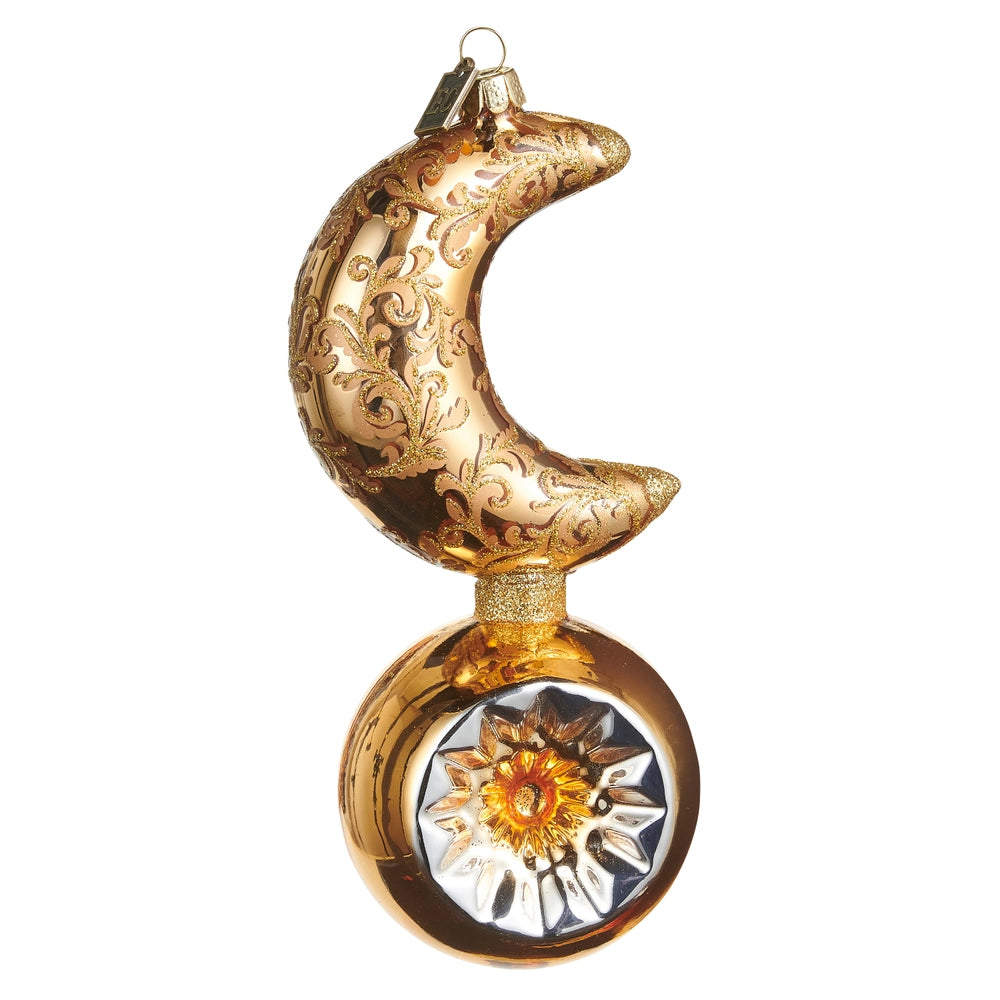 A decorative crescent moon and sun glass ornament with ornate gold scrollwork on the moon and a silver-toned sunburst design on the sun, set against a plain white background.