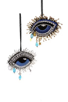 Decorative evil eye with eye lashes charm with blue centers and gold accents on a white background