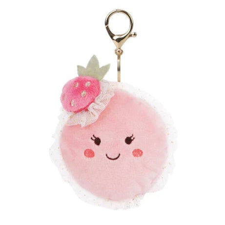 Pink macaron pom-pom keychain with a smiling face and flower on a white background