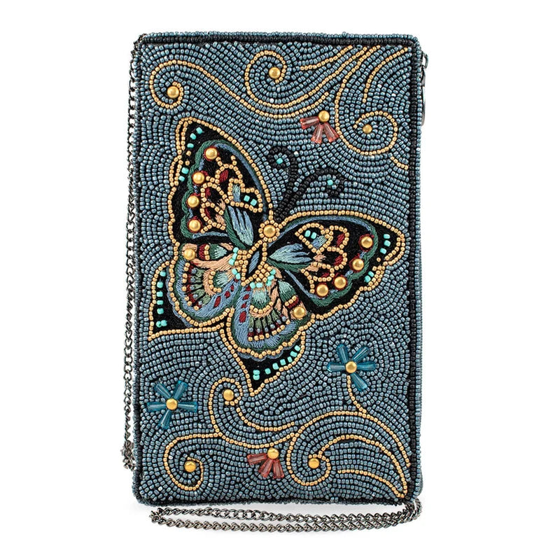 A rectangular beaded clutch bag with a detailed butterfly design in the center, featuring a slate blue-gray background with gold, teal, and pink accents, and a silver chain strap.