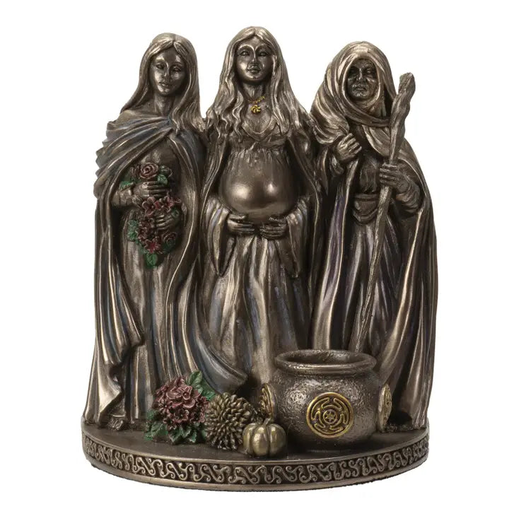 Decorative statue of three figures Mother, Maiden, Crone Goddesses with a cauldron and herbs on a white background