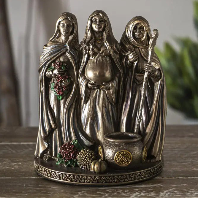 Decorative figurine of three hooded figures on a wooden surface