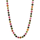 A beaded necklace made of faceted gemstone beads in pink, green, orange, and black tourmaline, separated by small gold spacer beads, shown on a plain white background.