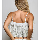 A woman shown from the back wearing a white ruffled camisole top and matching floral-print skirt against a plain gray studio background.