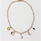 A gold-toned paperclip chain necklace with multiple celestial and abstract charms, including a sun, moon, crescent moon, black and white moon phases, a star, and a small black bead, displayed on a clean white background.