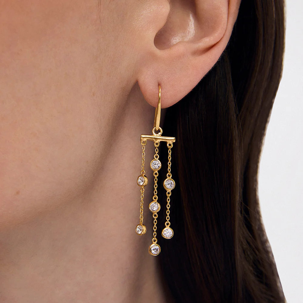 Gold earring with dangling Cubic Zirconias worn by a person