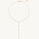 Gold necklace with small beads on a light beige background