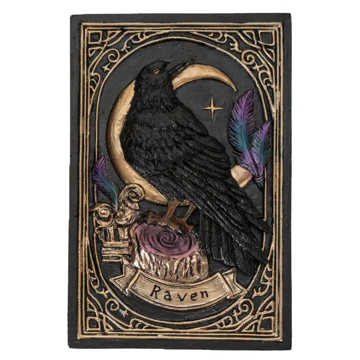 A gothic-style carved plaque featuring a black raven perched on a crescent moon above a rose, with purple feathers and the word 'Raven' on a banner, set against a dark background with ornate gold detailing.