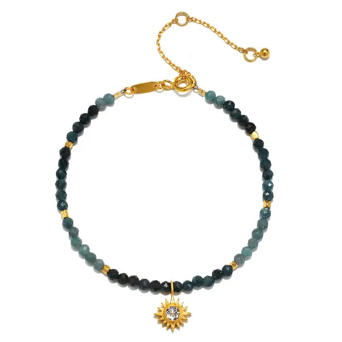 Bracelet with Sapphire beads and a gold sun pendant on a white background