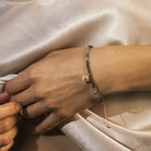 Close-up of a hand wearing a bracelet on a light fabric background