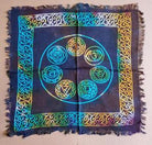 Colorful chakra symbol on a blue fabric square with intricate patterns.