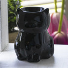 Black cat-shaped oil diffuser on a light wooden surface with a blurred background