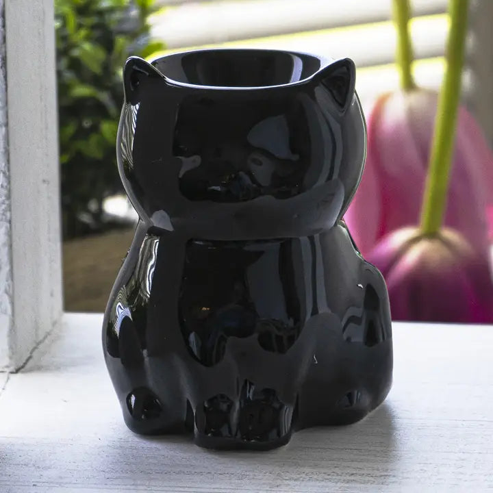 Black cat-shaped oil diffuser on a light wooden surface with a blurred background