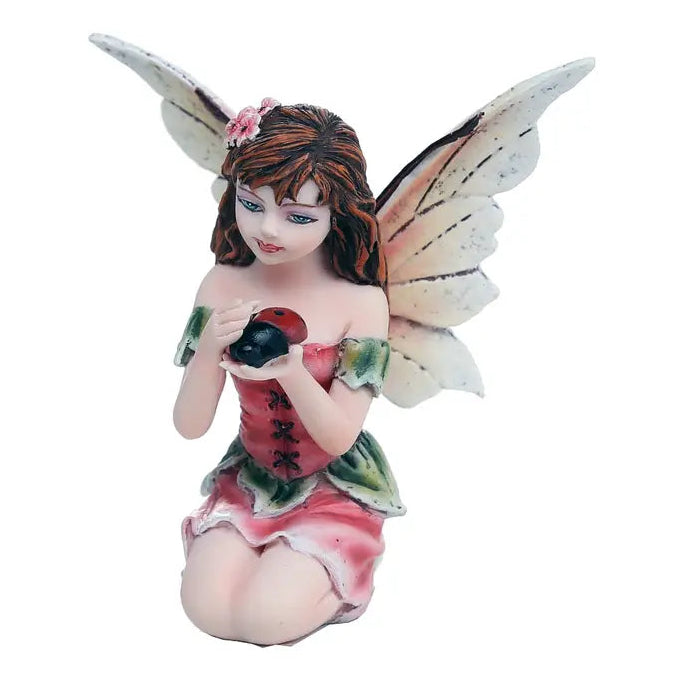 Fairy figurine with wings holding a blackberry on a white background