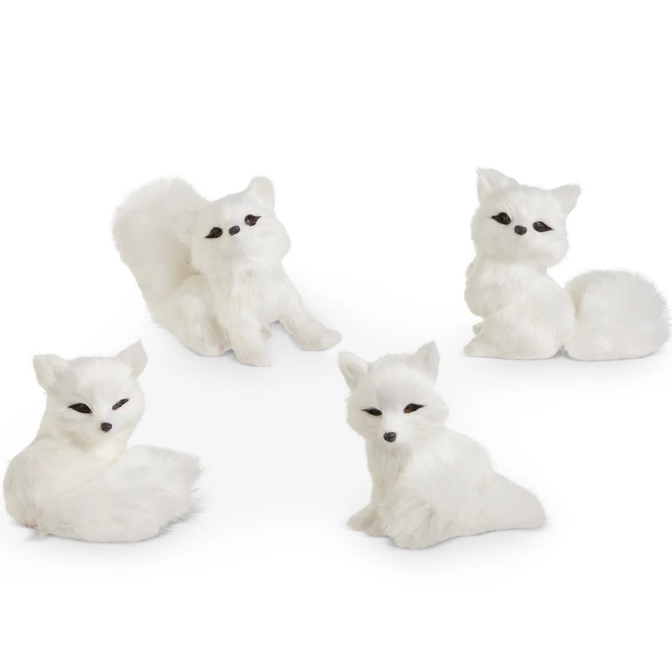 Four white faux-fur fox figurines shaped like foxes in different sitting poses, photographed on a clean white background.