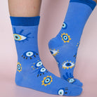 Blue socks with eye pattern worn by a person on a light pink background