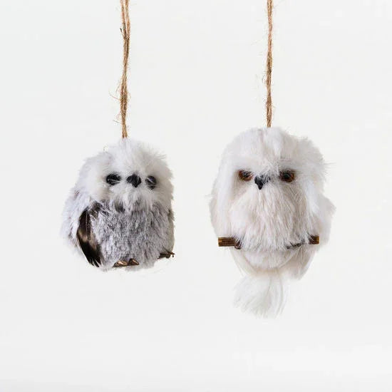 Two fluffy owl-shaped ornaments hanging on twine against a white background