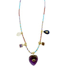 A bohemian-style beaded necklace with a large purple amethyst heart pendant, gold-tone chain and settings, and multiple colorful gemstone charms including blue, purple, white, and brown on a plain white background.