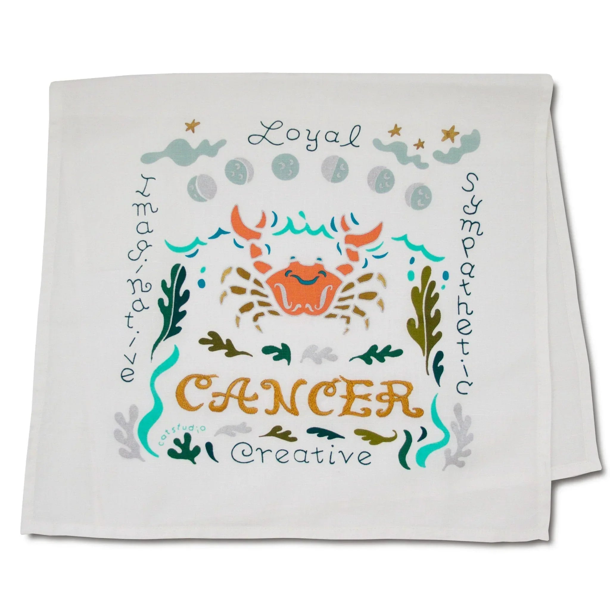 Cancer zodiac sign design on a folded white towel with decorative elements.