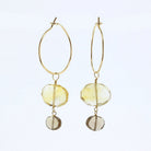 A pair of gold hoop drop earrings featuring faceted yellow citrine and smoky quartz  gemstone charms, displayed against a clean white background.