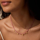 Close-up of a person wearing a pink Rhodonite beaded necklace with gold accents.