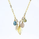 A gold paperclip chain necklace featuring a central Y-shaped arrangement with five dangling gemstone beads in blue, cream, pale pink, and yellow, set against a plain white background.