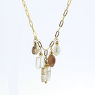 A gold chain necklace featuring a multi-stone pendant with a white pearl, a rectangular rutilated quartz  clear stone, a brown stone, and a vertical clear rectangle stone with gold inclusions, set against a plain white background.