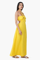Woman wearing a yellow dress with cut-out sides on a white background