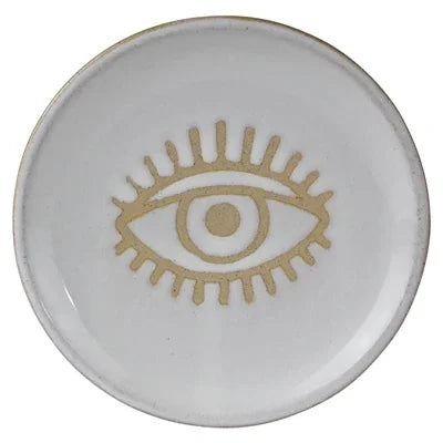 Round ceramic dish with a gold eye design on a white background