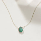 Necklace with a green emerald teardrop pendant on a white background