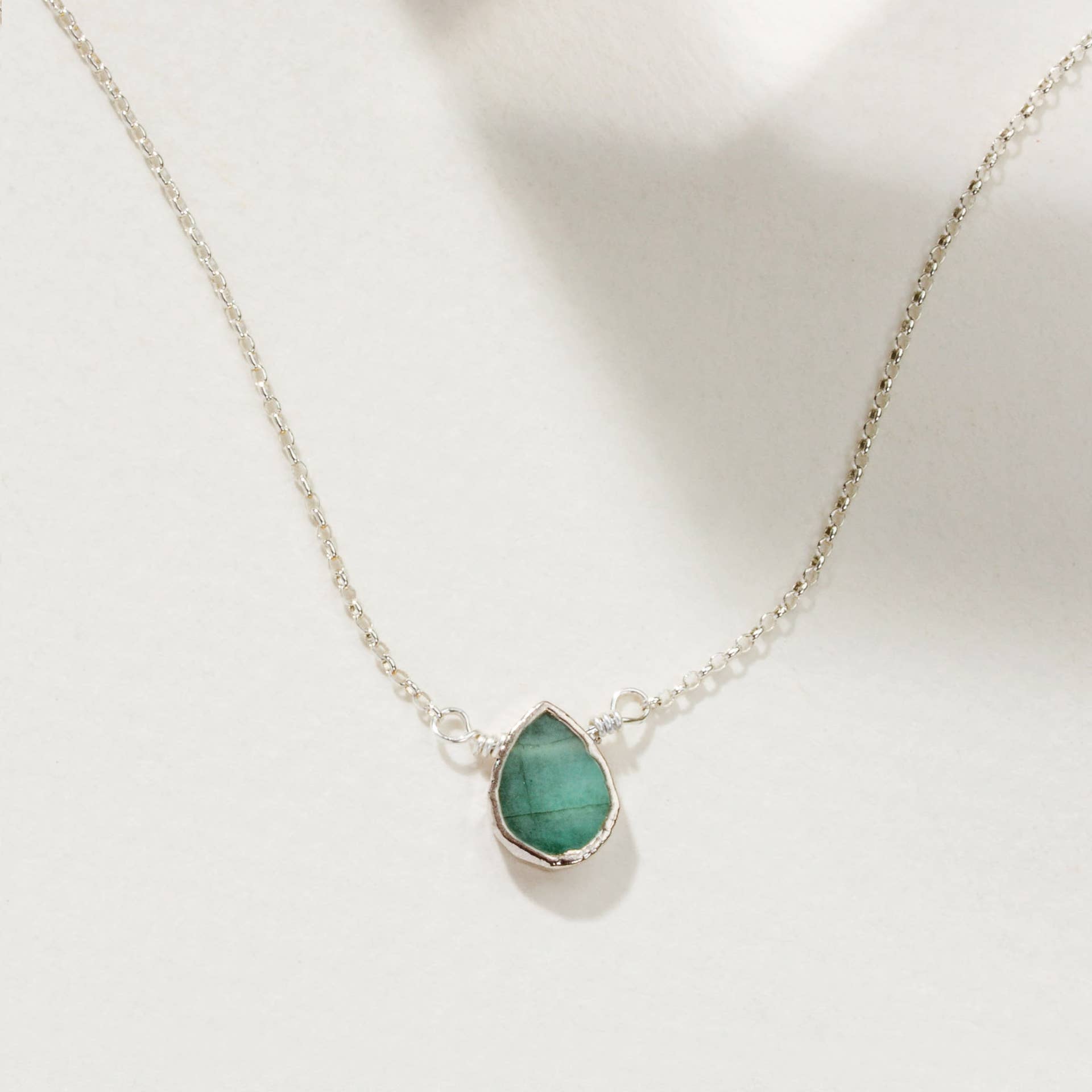 Necklace with a green emerald teardrop pendant on a white background