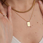 Gold necklace with a pendant on a person's neck