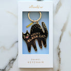 Black cat enamel keychain in packaging on a marble surface