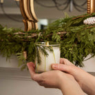 Frasier Fir Pine Needle Candle alongide a holiday wreath