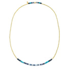 A delicate gold beaded necklace with a central horizontal row of small blue, turquoise, and white beads, displayed on a clean white background.