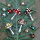 Mushroom-shaped Christmas ornaments on a leaf with a wooden background