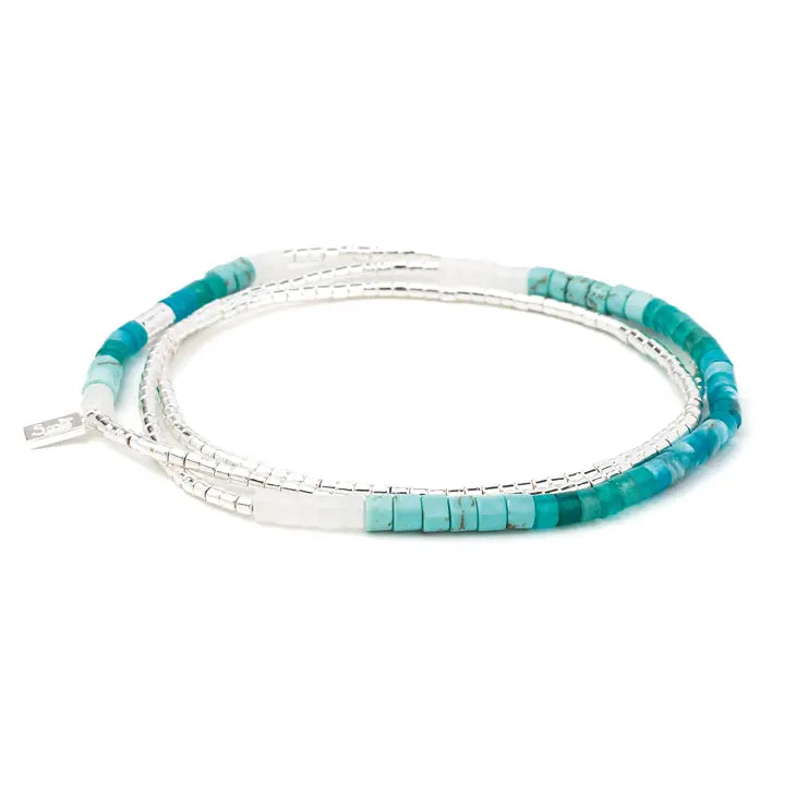 Turquoise beaded bracelet with silver accents on a white background