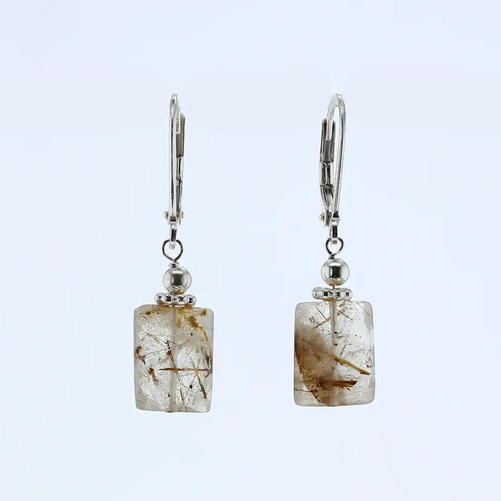 A pair of silver leverback earrings featuring rectangular clear rutilated quartz with visible brown and gold mineral inclusions, set against a plain light blue background.