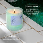 Candle labeled 'Spa Water' on a tiled surface near water, with text describing its fragrance.