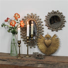 Decorative wall mirrors and candle holders on a wooden surface with flowers and candles.