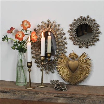 Decorative wall mirrors and candle holders on a wooden surface with flowers and candles.