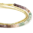 Set of beaded bracelets with gold, purple, and green beads on a white background