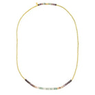 A gold beaded necklace with a curved bar of multicolor gemstone beads at the bottom, displayed on a clean white background.